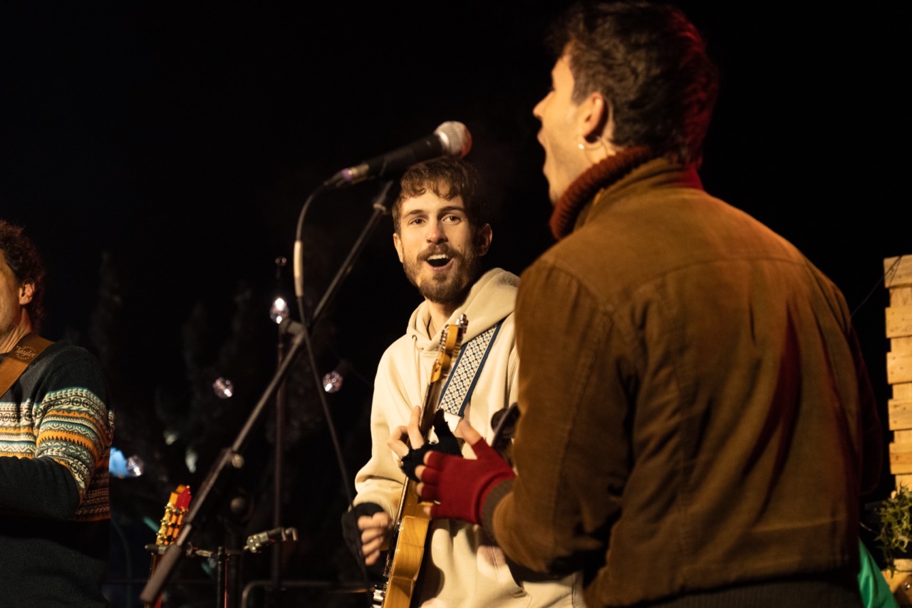 Cantant de Col·lectiu Desembre en primer pla amb la banda darrere